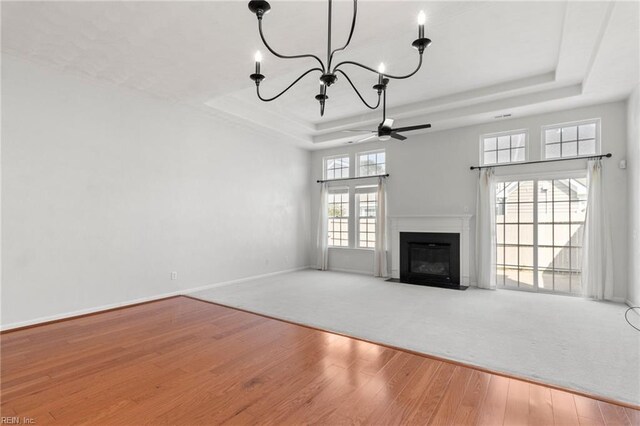 310 Lighthouse Way, Carrollton, VA 23314 - unfurnished living room featuring a tray ceiling, hardwood / wood-style floors, a chandelier, ceiling fan, and a fireplace with flush hearth
