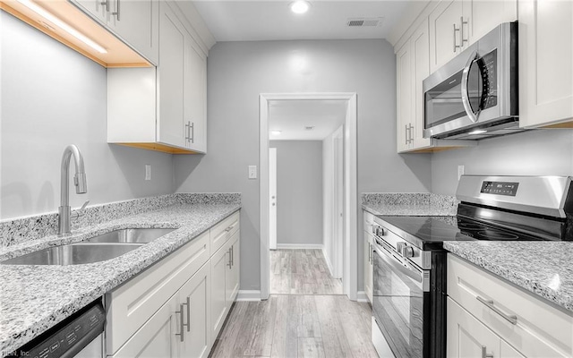 3506 Somme Ave, Norfolk, VA 23509 - kitchen with stainless steel appliances, a sink, light wood-type flooring, white cabinets, and light stone counters
