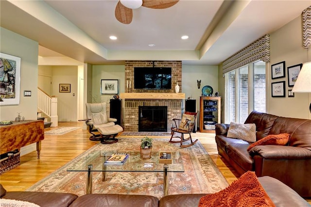 140 Hearthside Ln, Williamsburg, VA 23185 - living area featuring wood finished floors, stairs, a ceiling fan, a brick fireplace, and a raised ceiling