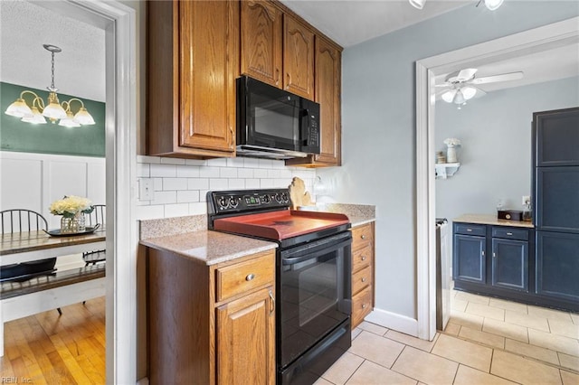 6615 Cabot Ave, Norfolk, VA 23502 - kitchen featuring black appliances, decorative backsplash, a chandelier, brown cabinetry, and light tile patterned floors
