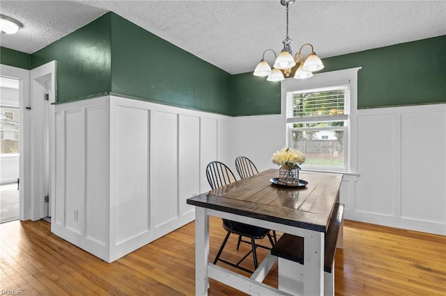 6615 Cabot Ave, Norfolk, VA 23502 - dining room featuring a decorative wall, a textured ceiling, light wood finished floors, a chandelier, and wainscoting