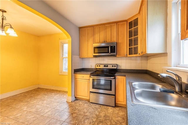 409 Wingfield Ave, Chesapeake, VA 23325 - kitchen featuring appliances with stainless steel finishes, a sink, dark countertops, decorative backsplash, and arched walkways