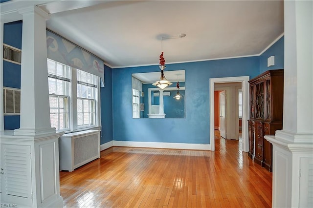 751 Shirley Ave, Norfolk, VA 23517 - unfurnished dining area featuring ornate columns, radiator heating unit, light wood-style flooring, baseboards, and crown molding