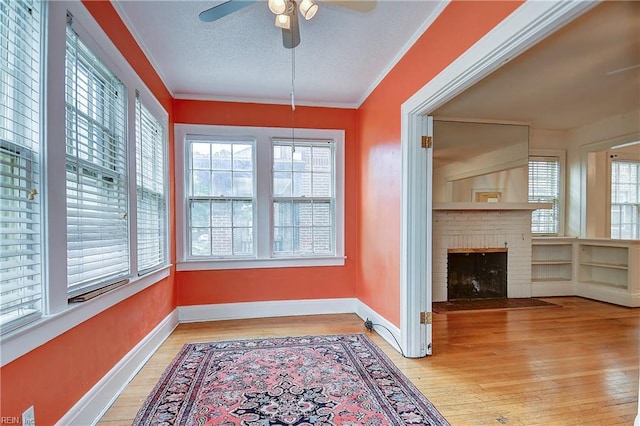751 Shirley Ave, Norfolk, VA 23517 - unfurnished dining area featuring a ceiling fan, light wood finished floors, a textured ceiling, a fireplace, and baseboards