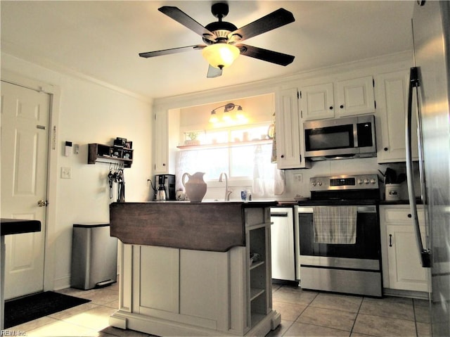 21139 Reynolds Dr, Carrollton, VA 23314 - kitchen with stainless steel appliances, light tile patterned floors, crown molding, white cabinets, and dark countertops