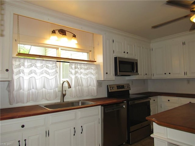 21139 Reynolds Dr, Carrollton, VA 23314 - kitchen featuring appliances with stainless steel finishes, a sink, butcher block counters, white cabinetry, and ornamental molding