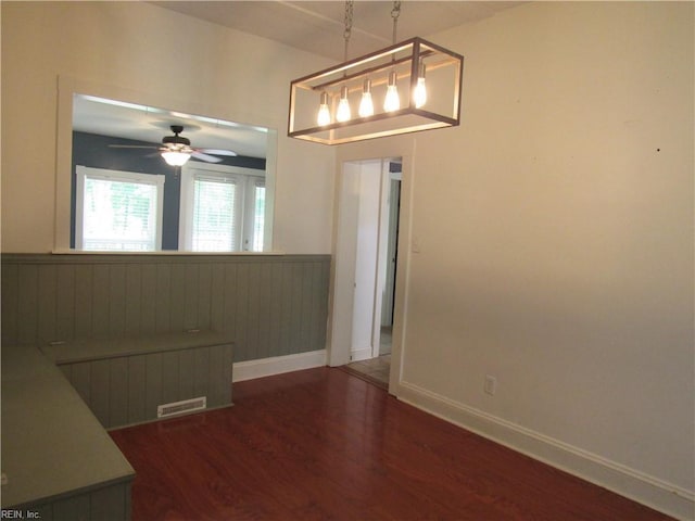 21139 Reynolds Dr, Carrollton, VA 23314 - unfurnished dining area featuring wainscoting, dark wood-style floors, a ceiling fan, and baseboards