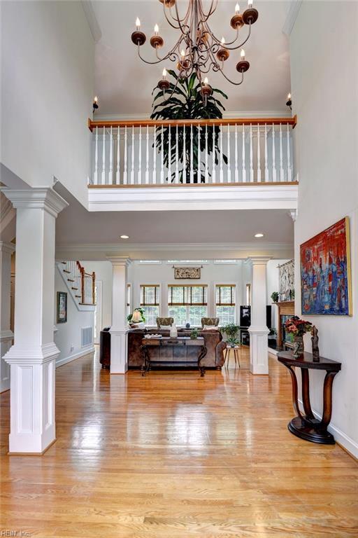 2081 Harpers Ml, Williamsburg, VA 23185 - living room with a high ceiling, decorative columns, light wood-style floors, a chandelier, and crown molding