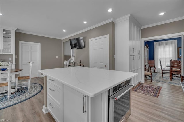 136 Wynnwood Dr, Franklin, VA 23851 - kitchen with stainless steel oven, light wood-style flooring, white cabinets, ornamental molding, and a kitchen island