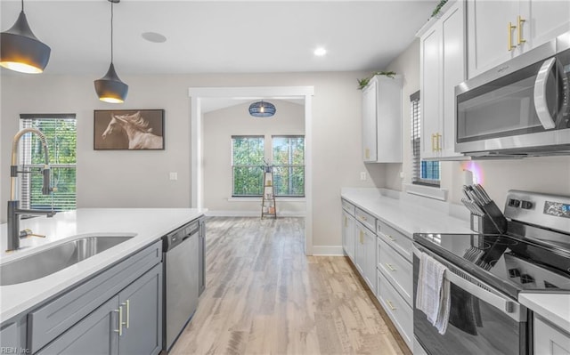 126 Secretariat Dr, Suffolk, VA 23435 - kitchen with stainless steel appliances, a sink, light wood-style floors, light countertops, and hanging light fixtures
