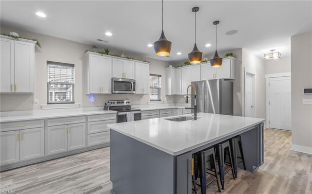 126 Secretariat Dr, Suffolk, VA 23435 - kitchen featuring stainless steel appliances, a sink, a breakfast bar, light countertops, and light wood finished floors