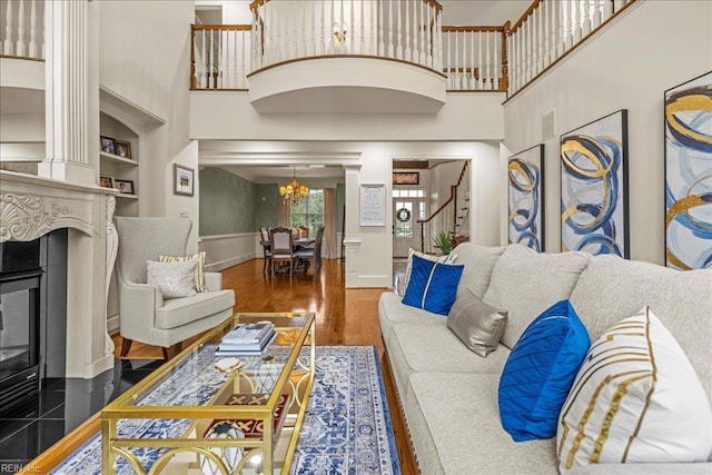 201 Royal Dornoch, Smithfield, VA 23430 - living room featuring a glass covered fireplace, a chandelier, wood finished floors, stairway, and decorative columns