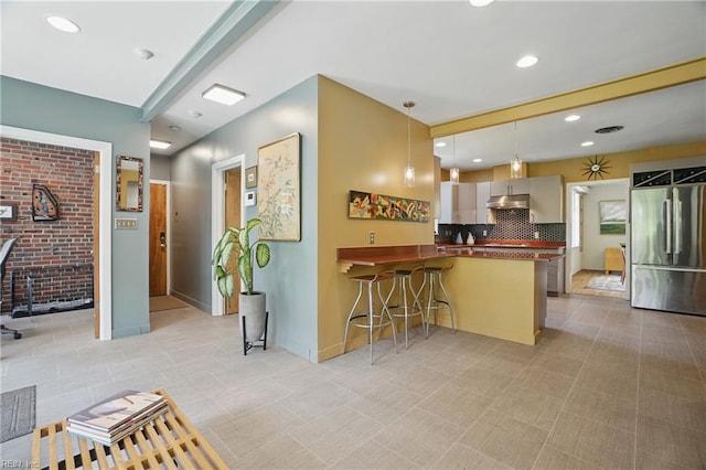 6076 Newport Pt, Norfolk, VA 23505 - kitchen featuring stainless steel fridge, under cabinet range hood, a peninsula, dark countertops, and recessed lighting
