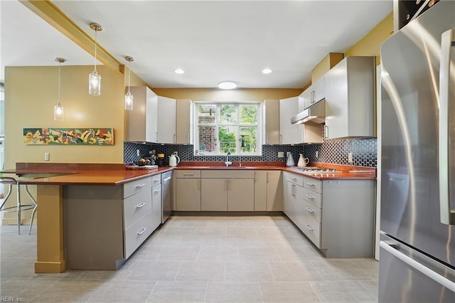 6076 Newport Pt, Norfolk, VA 23505 - kitchen featuring appliances with stainless steel finishes, dark countertops, a peninsula, backsplash, and under cabinet range hood