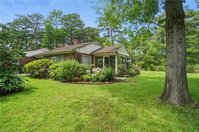 6076 Newport Pt, Norfolk, VA 23505 - view of home's exterior with a chimney, brick siding, a yard, and a sunroom