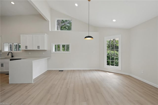 1202 Land St, Norfolk, VA 23502 - kitchen with light countertops, white cabinetry, light wood-style flooring, high vaulted ceiling, and a peninsula
