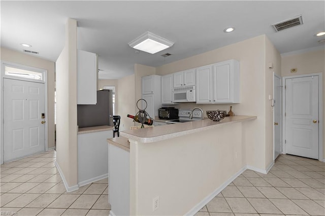 4700 Martinique Ct Unit 12, Virginia Beach, VA 23455 - kitchen with white microwave, stove, freestanding refrigerator, light tile patterned flooring, and white cabinetry