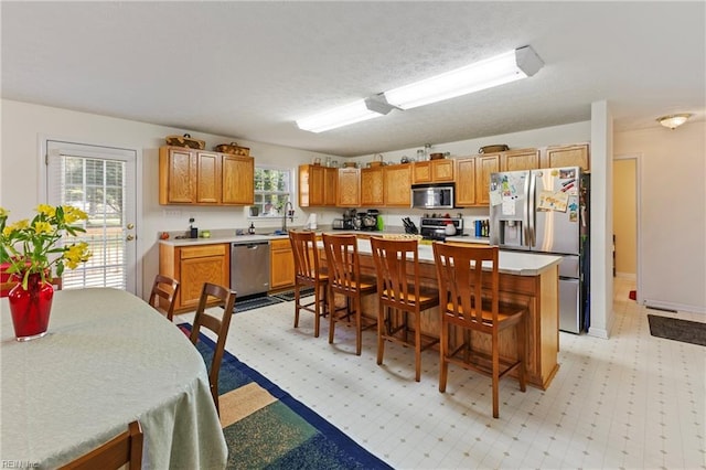 103 Barcroft Dr, Smithfield, VA 23430 - kitchen with stainless steel appliances, a breakfast bar, light countertops, a kitchen island, and brown cabinets