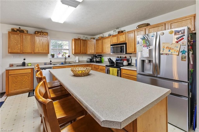 103 Barcroft Dr, Smithfield, VA 23430 - kitchen with stainless steel appliances, a sink, a textured ceiling, light countertops, and a center island