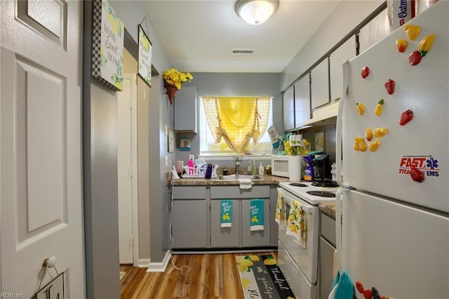 2117 King James Ct, Carrollton, VA 23314 - kitchen featuring white appliances, a sink, light wood finished floors, under cabinet range hood, and baseboards