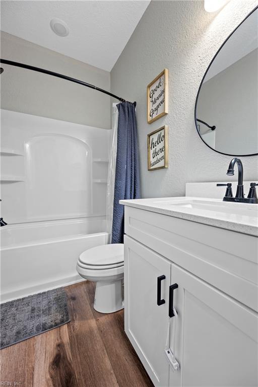 554 Trotman Rd, Camden, NC 27921 - full bath featuring vanity, wood finished floors, toilet, shower / bath combination with curtain, and a textured wall