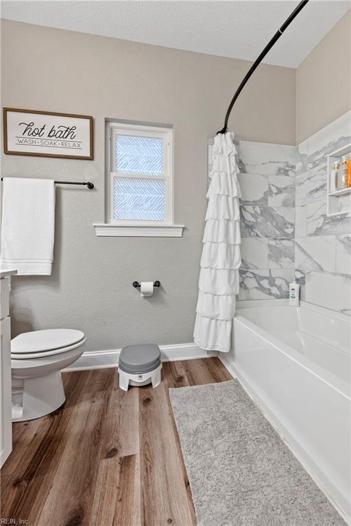554 Trotman Rd, Camden, NC 27921 - full bath featuring toilet, wood finished floors, shower / bathtub combination with curtain, and baseboards