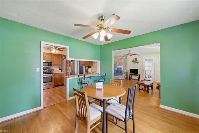 1348 Carlton Ct, Norfolk, VA 23503 - dining space featuring light wood-type flooring, a ceiling fan, baseboards, and a fireplace
