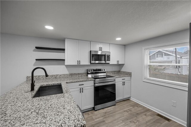 1305 Canary Dr, Virginia Beach, VA 23453 - kitchen featuring stainless steel appliances, a sink, open shelves, light wood-style flooring, and white cabinetry