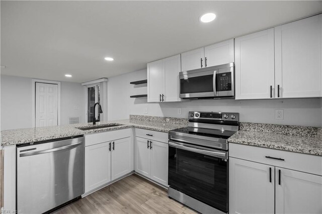 1305 Canary Dr, Virginia Beach, VA 23453 - kitchen featuring appliances with stainless steel finishes, a sink, open shelves, white cabinetry, and light wood-style flooring