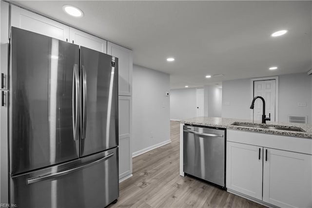 1305 Canary Dr, Virginia Beach, VA 23453 - kitchen featuring appliances with stainless steel finishes, a sink, light wood-type flooring, light stone countertops, and white cabinets