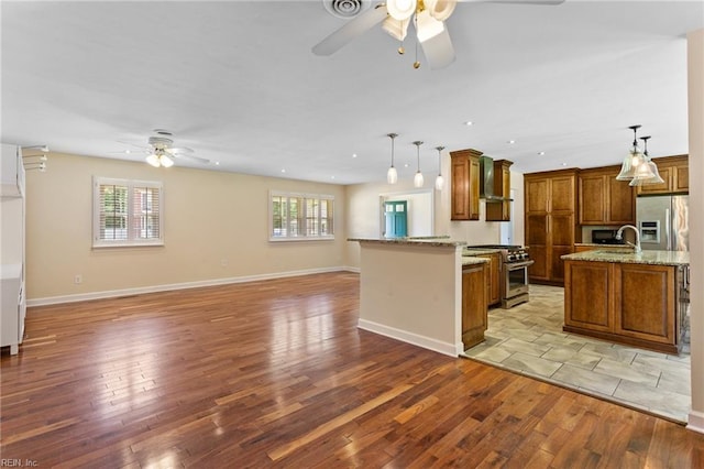 4901 Lake Shore Dr, Chesapeake, VA 23321 - kitchen with stainless steel appliances, ceiling fan, wall chimney exhaust hood, brown cabinetry, and open floor plan