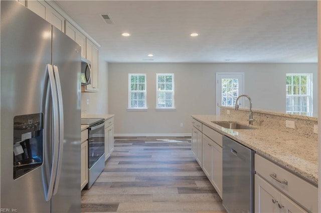 2807 Eustis Ave, Chesapeake, VA 23325 - kitchen featuring appliances with stainless steel finishes, a sink, light wood finished floors, recessed lighting, and light stone countertops