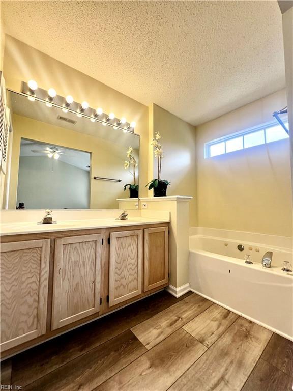 2511 Hartley St, Virginia Beach, VA 23456 - full bathroom with wood finished floors, double vanity, a bath, a textured ceiling, and ceiling fan