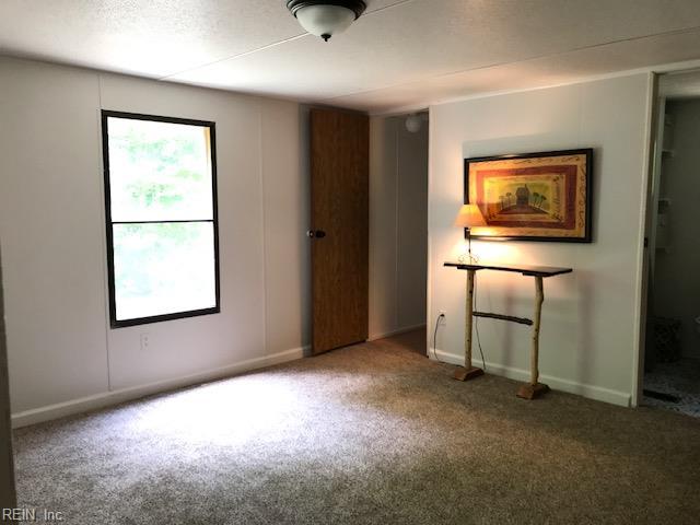 9917 Friendship Rd, North, VA 23128 - unfurnished bedroom featuring multiple windows, carpet flooring, and baseboards