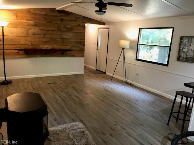 9917 Friendship Rd, North, VA 23128 - unfurnished living room with a ceiling fan, dark wood-style floors, baseboards, and wooden walls