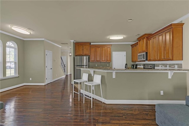 7556 Villa Ct, Gloucester, VA 23061 - kitchen with stainless steel appliances, crown molding, a kitchen bar, brown cabinets, and a peninsula
