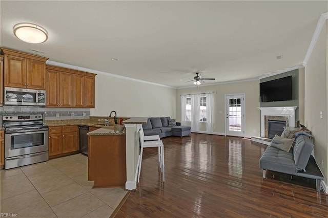 7556 Villa Ct, Gloucester, VA 23061 - kitchen featuring stainless steel appliances, open floor plan, a sink, a peninsula, and ornamental molding