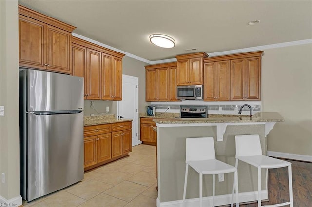 7556 Villa Ct, Gloucester, VA 23061 - kitchen featuring appliances with stainless steel finishes, brown cabinets, light stone countertops, ornamental molding, and baseboards
