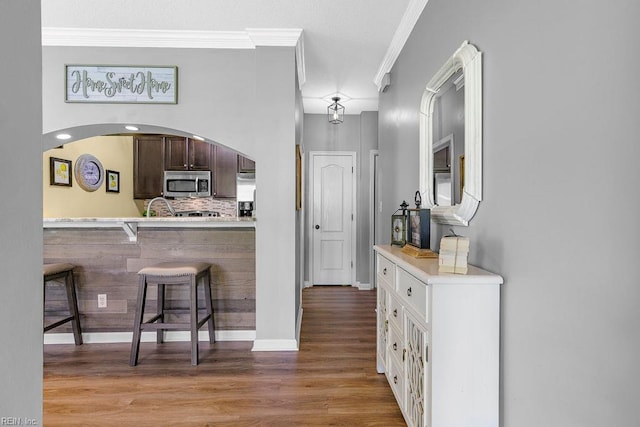 3101 Bridgewater Dr, Carrollton, VA 23314 - kitchen with appliances with stainless steel finishes, a breakfast bar area, crown molding, light countertops, and light wood-style flooring
