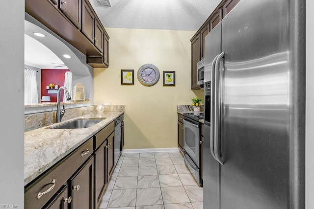 3101 Bridgewater Dr, Carrollton, VA 23314 - kitchen with appliances with stainless steel finishes, a sink, light marble finish floors, dark brown cabinets, and light stone counters