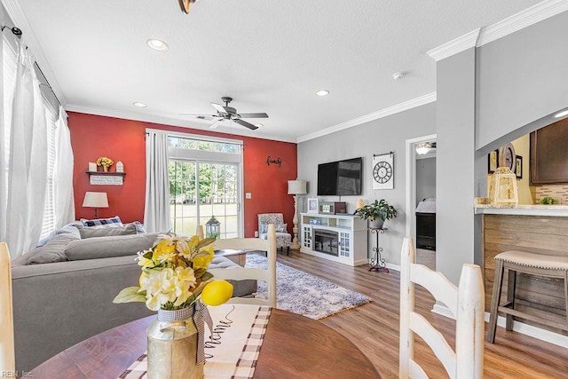 3101 Bridgewater Dr, Carrollton, VA 23314 - living room featuring a glass covered fireplace, wood finished floors, recessed lighting, crown molding, and a ceiling fan