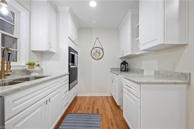 166 Windward Way, Port Haywood, VA 23138 - kitchen with a sink, light wood-style flooring, white cabinetry, open shelves, and light stone countertops