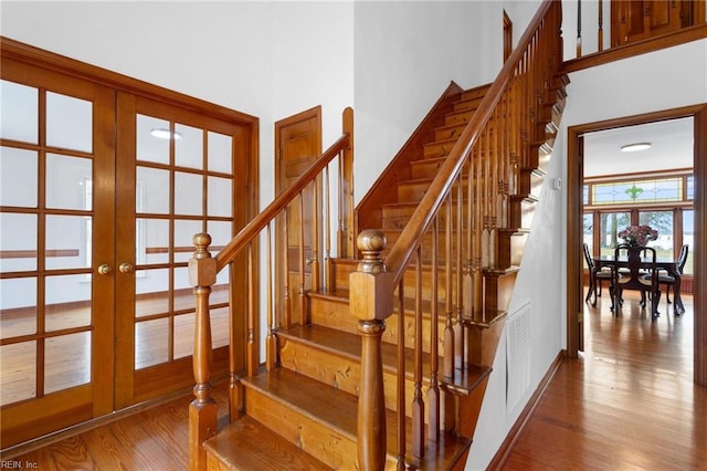 2543 Bridge Rd, Suffolk, VA 23435 - staircase with french doors, wood finished floors, a towering ceiling, and baseboards