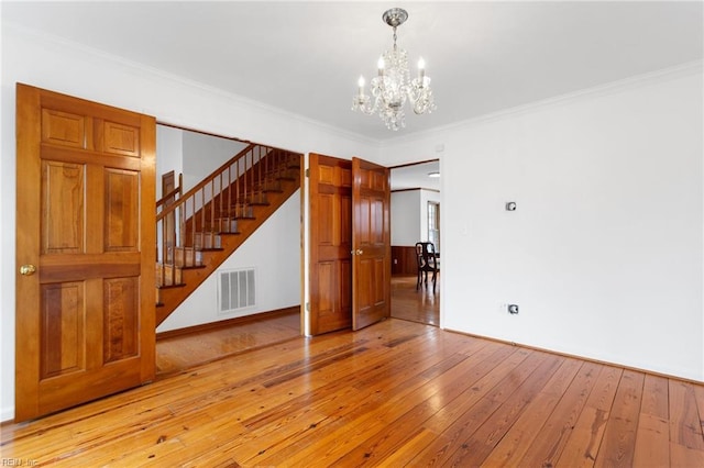 2543 Bridge Rd, Suffolk, VA 23435 - unfurnished living room featuring stairs, a chandelier, light wood-type flooring, crown molding, and baseboards