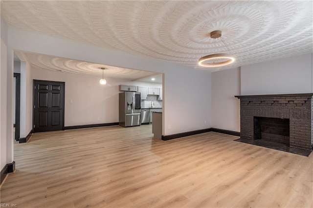 1943 Sycamore Ln, Norfolk, VA 23523 - unfurnished living room featuring baseboards, light wood-type flooring, and a brick fireplace