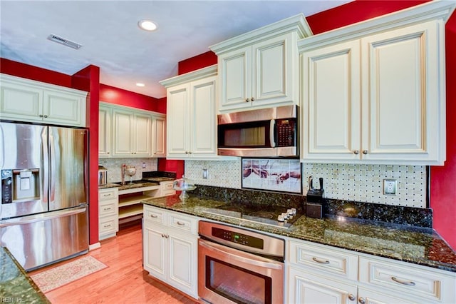 313 Queen Ct, Smithfield, VA 23430 - kitchen with appliances with stainless steel finishes, dark stone countertops, light wood-type flooring, backsplash, and recessed lighting
