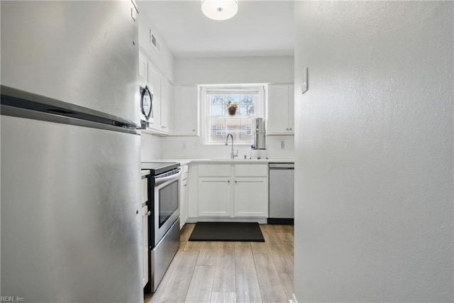 882 Elizabeth Ct, Virginia Beach, VA 23451 - kitchen with stainless steel appliances, a sink, white cabinets, and light wood finished floors