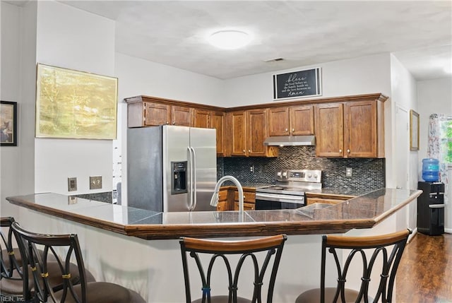 127 Rockland Ter, Suffolk, VA 23434 - kitchen featuring stainless steel appliances, under cabinet range hood, brown cabinetry, a peninsula, and tasteful backsplash