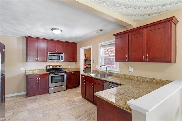 2811 Mapleton Ave, Norfolk, VA 23504 - kitchen featuring appliances with stainless steel finishes, a sink, dark brown cabinets, a peninsula, and light stone countertops