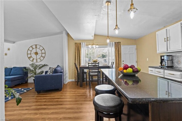 1208 Santeetlah Ave, Chesapeake, VA 23325 - kitchen with vaulted ceiling, light wood-style flooring, white cabinetry, a chandelier, and hanging light fixtures